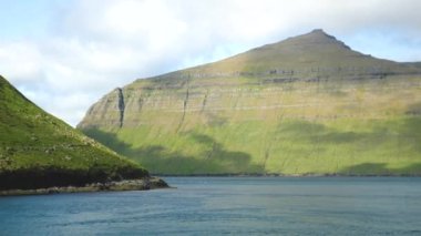 Ferry arriving to Kalsoy Island. Amazing Faroese nature. Faroese Cliffs and mountains. Green hills and beautiful rocky mountains. View to a Kalsoy Island. Sunny day in summer. 4k footage