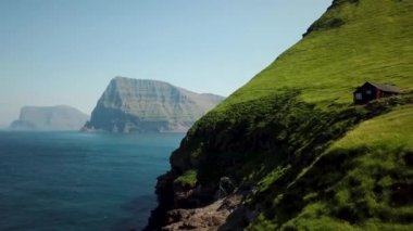Aerial view of Kalsoy island, Faroe Islands. Amazing Faroese nature, green hills and beautiful rocky cliffs and mountains. Kallur lighthouse. Sunny day in summer. Movie Island in Faroe. 4k footage