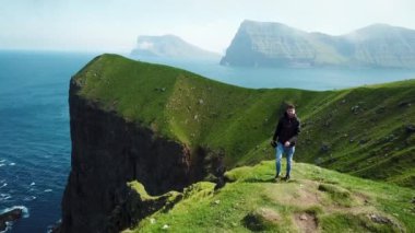 Kalsoy, Faroe Islands - August 23, 22: Aerial view of Kalsoy island. Amazing Faroese nature, green hills and beautiful rocky cliffs and mountains. Kallur lighthouse. Sunny day in summer. 4k footage