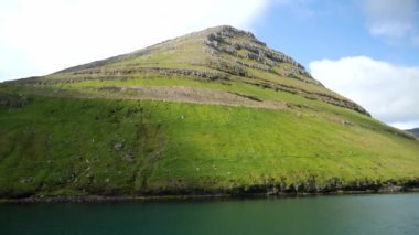 Ferry arriving to Kalsoy Island. Amazing Faroese nature. Faroese Cliffs and mountains. Green hills and beautiful rocky mountains. View to a Kalsoy Island. Sunny day in summer. 4k footage