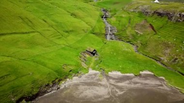 Aerial view of a lonely house with a lagoon in Saksun village, Faroe Islands. Lagoon in beautiful green nature in Saksun. Mist faroese nature. High quality 4k footage. Lonely house in a wild nature.