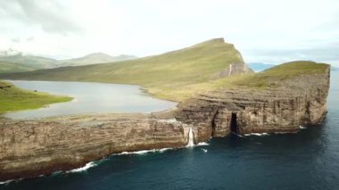 Aerial view of Slave cliff or Traelanipan and Sorvagsvatn lake or Leitisvatn, Biggest lake in Faroe Islands. Amazing nature. Huge cliffs. Lake above the ocean. Bosdalafossur waterfall. 4k footage.