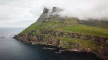 Aerial view of Arnafjall mountain hidden in a fog, Faroe Islands. Small village Gasadalur with a Hvannadalur valley. High quality 4k footage.