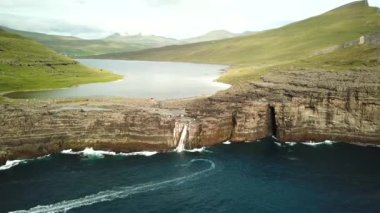 Aerial view of Slave cliff or Traelanipan and Sorvagsvatn lake or Leitisvatn, Biggest lake in Faroe Islands. Amazing nature. Huge cliffs. Lake above the ocean. Bosdalafossur waterfall by boat. 4k.