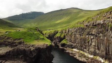 Aerial view of a canyon in Gjogv village in Faroe Islands. Sunny day in summer. Amazing nature in Faroe Islands. Eysturoy. Faroese canyon. Natural harbour in Gjogv. Slaettaratindur in the background.