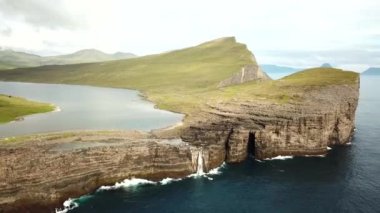 Aerial view of Slave cliff or Traelanipan and Sorvagsvatn lake or Leitisvatn, Biggest lake in Faroe Islands. Amazing nature. Huge cliffs. Lake above the ocean. Bosdalafossur waterfall. 4k footage.