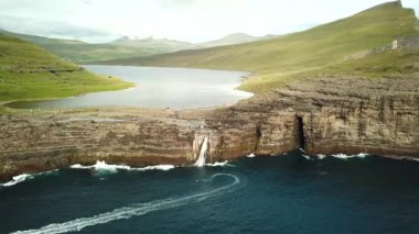 Aerial view of Slave cliff or Traelanipan and Sorvagsvatn lake or Leitisvatn, Biggest lake in Faroe Islands. Amazing nature. Huge cliffs. Lake above the ocean. Bosdalafossur waterfall by boat. 4k.