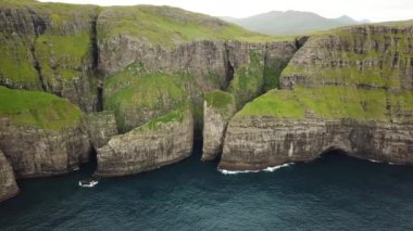 Faroe Adaları, Dunnesdrangar 'ın insansız hava aracı görüntüsü. İnanılmaz doğa, Faroe Adaları 'ndaki büyük kayalıklar ve dağlar. Vagar Adası. Bir sürü uçan deniz kuşu. Yazın güneşli bir gün. Yüksek kalite 4k görüntü. 
