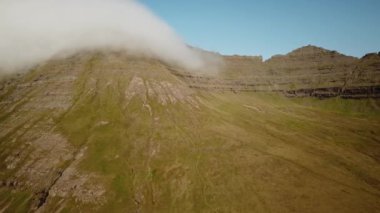 Faroe Adaları, Villingadalsfall hava aracı görüntüsü. İnanılmaz doğa, Faroe Adaları 'ndaki büyük kayalıklar ve dağlar. Vidoy Adası. Yazın güneşli bir gün. Yüksek kalite 4k görüntü. 