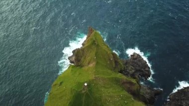 Faroe Adaları 'ndaki Kalsoy adasındaki uçurumların insansız hava aracı görüntüsü. Muhteşem Faroe doğası, yeşil tepeler ve güzel kayalıklar ve dağlar. Kallur deniz feneri. Yazın güneşli bir gün. Kaliteli 4k görüntü.