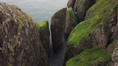 Faroe Adaları, Dunnesdrangar 'ın insansız hava aracı görüntüsü. İnanılmaz doğa, Faroe Adaları 'ndaki büyük kayalıklar ve dağlar. Vagar Adası. Bir sürü uçan deniz kuşu. Yazın güneşli bir gün. Yüksek kalite 4k görüntü. 