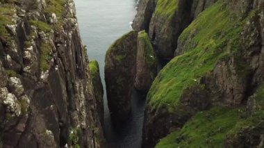 Faroe Adaları, Dunnesdrangar 'ın insansız hava aracı görüntüsü. İnanılmaz doğa, Faroe Adaları 'ndaki büyük kayalıklar ve dağlar. Vagar Adası. Bir sürü uçan deniz kuşu. Yazın güneşli bir gün. Yüksek kalite 4k görüntü. 