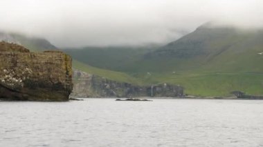 Faroe Adaları 'ndaki sis içinde gizlenmiş kayalıklardan ve Vagar adasından manzara. Atlantik Okyanusu 'ndaki kaya oluşumları. Yüksek kalite 4k görüntü.