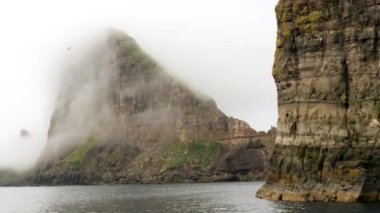 Faroe Adaları 'ndaki Atlantik Okyanusu' nda gizlenmiş Tindholmur ve Drangarnir 'in teknesinden bir görüntü. Kaya oluşumları Tindholmur ve Drangarnir Deniz Yığını adacıkları. Yüksek kalite 4k görüntü.
