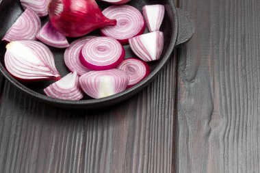 Mor soğanları halkalara ve soğanları kızartma tavasına dilimledim. Koyu ahşap arka plan. Uzayı kopyala Üst görünüm