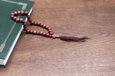 Kitap ve haçlı kahverengi tespih. Uzayı kopyala Ahşap arkaplan