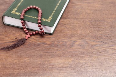 Yeşil Kitap ve haçlı kahverengi tespih. Uzayı kopyala Ahşap arkaplan