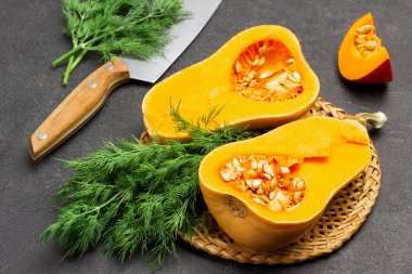 Hasır tabakta balkabağı yarımları ve bir demet dereotu. Dill ve mutfak bıçağı masada. Üst Manzara. Siyah arkaplan