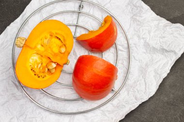 Portakal kabağı yarımları beyaz kağıt üzerinde metal ayakta duruyor. Siyah arka plan. Düz yatıyordu.