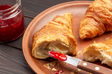 Bıçaklı reçel ve seramik tabakta kruvasan. Reçel kavanozu. Kapat.. 