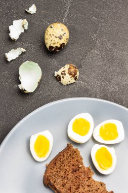 Gri tabakta tost ve haşlanmış bıldırcın yumurtası. Mermiler masada. Üst Manzara. Siyah arkaplan.