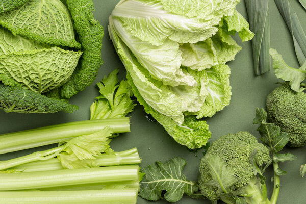 Celery stalks, leek, Chinese cabbage, broccoli and Savoy cabbage. Flat lay. Green background.