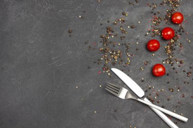 Kırmızı domatesler ve tüm baharatlar masada. Çatal ve bıçak. Uzayı kopyala Düz yatıyordu. Siyah arkaplan.