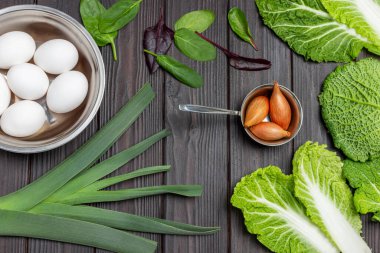 Metal kasede yumurta, pırasa ve arpacık soğanı ıspanak yaprağı ve savoy lahanası. Düz yatıyordu. Ahşap arkaplan. 