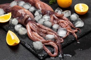Buz ve limonlu dokunaçlı taze mürekkep balığı. Kapatın. Üst Manzara. Siyah arkaplan