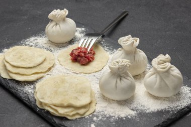 Et, mangır üstüne çatalla doluyor. Çiğ hamur köftesi, hamur parçaları ve un. Üst Manzara. Siyah arkaplan