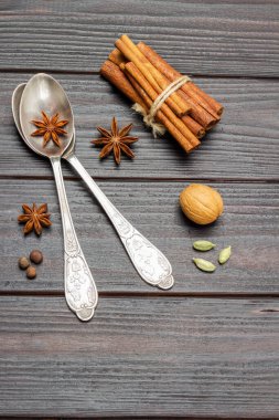 İki metal kaşık ve yıldız anason. Tarçın çubukları demetlere bağlanmış. Düz yatıyordu. Koyu tahta arkaplan.