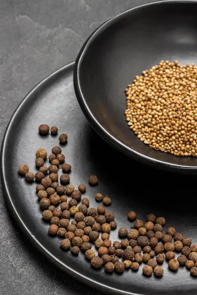 Siyah tabakta Allspice. Siyah kasede kişniş tohumları. Üst Manzara. Siyah arkaplan