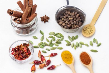 Metal kasede Allspice ve kavanozda tarçın çubukları. Baharatlı biber, zerdeçal ve zencefil. Kakule tohumları ve kırmızı biber kabukları. Üst Manzara. Beyaz arkaplan