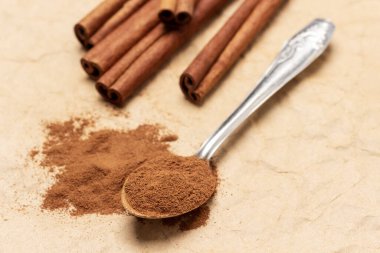 Yer tarçını metal kaşıkta ve masada. Üst Manzara. Arkaplan buruşuk kahverengi kağıt