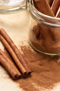 Tarçın çubukları, tarçın ve masa. Cam kavanozda tarçın çubukları. Kapatın. Kahverengi arkaplan.
