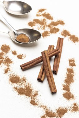 Tarçın çubukları tarçın arasında, metal kaşıklar masada. Kapatın. Üst Manzara. Beyaz arkaplan