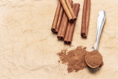 Metal kaşıkta tarçın. Tarçın çubukları. Uzayı kopyala Üst Manzara. Bej kağıt arkaplan