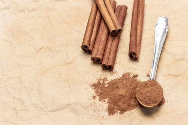 Metal kaşıkta tarçın. Tarçın çubukları. Uzayı kopyala Üst Manzara. Bej kağıt arkaplan