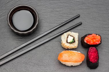 Suşi ve soya sosu kasede, yemek çubukları. Düz yatıyordu. Siyah arkaplan.