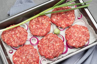 Çiğ sığır burger, doğranmış soğan ve yeşil soğanlı peçete tepsisi. Üst görünüm. 