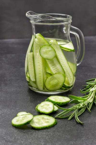 Cucumber Infused Water Glass Jug Sprig Rosemary Table Black Background — стоковое фото