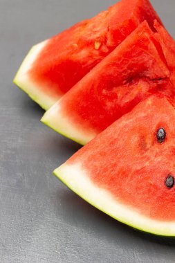 Three pieces of watermelon, part of the frame. Close up. Top view. Grey background.