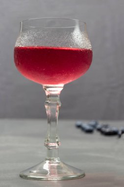 Wine glass with cooling drink. Drops of water on misted glass of wine glass. Grey background