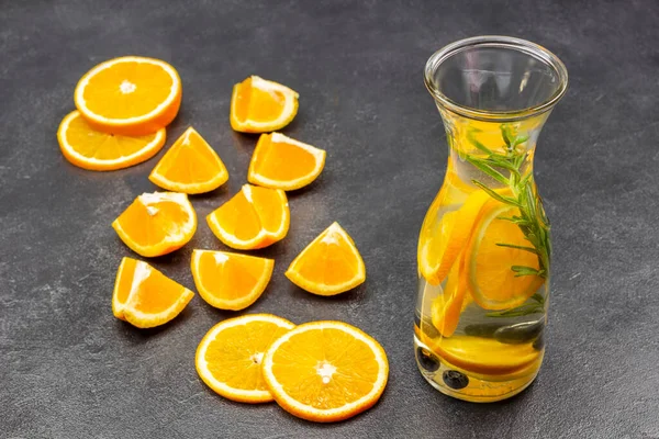 Orange slices on table. Orange infused water in glass bottle. Top view. Black background.