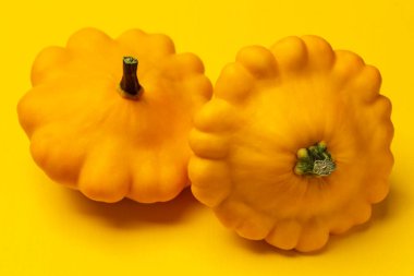 Two yellow patissons on a yellow background. top view
