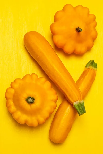 Two squash and two yellow zucchini. Flat lay. Yellow background