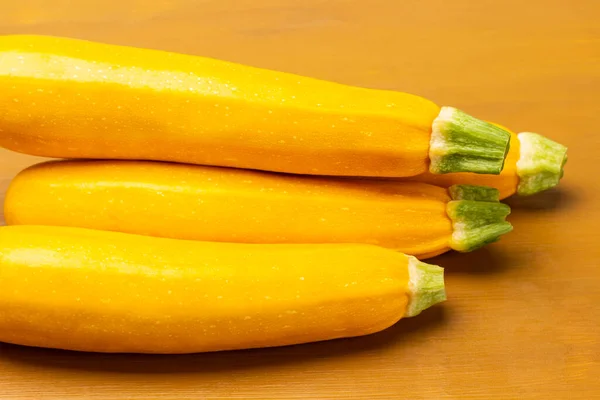 Yellow zucchini with green tails. Yellow background. Close up