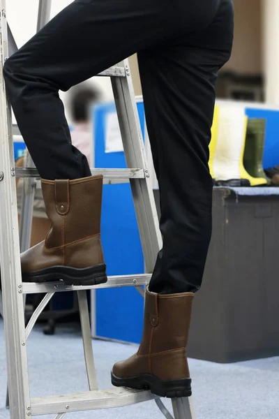 The workers are climbing the stairs wearing safety shoes made of leather to protect their feet from accidents at work. Safety footwear is part of the safety equipment