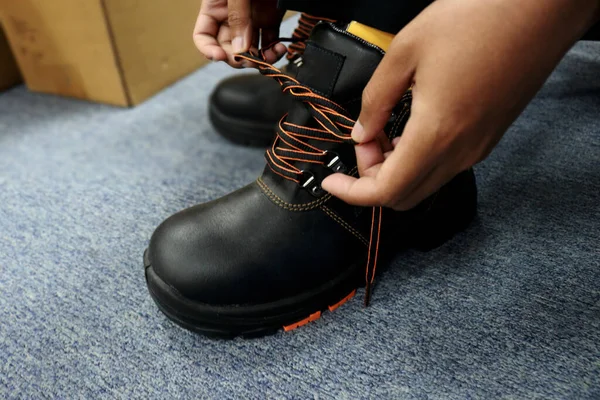 Bir erkek işçi işe hazırlanmak için ayakkabılarını bağlıyor.
