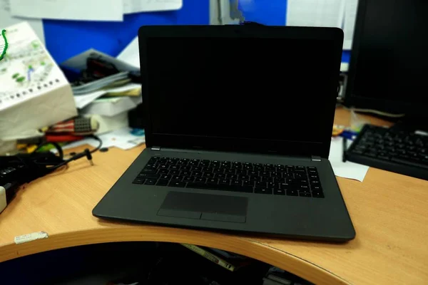 オフィスの机の上の黒いノートパソコンの写真 — ストック写真